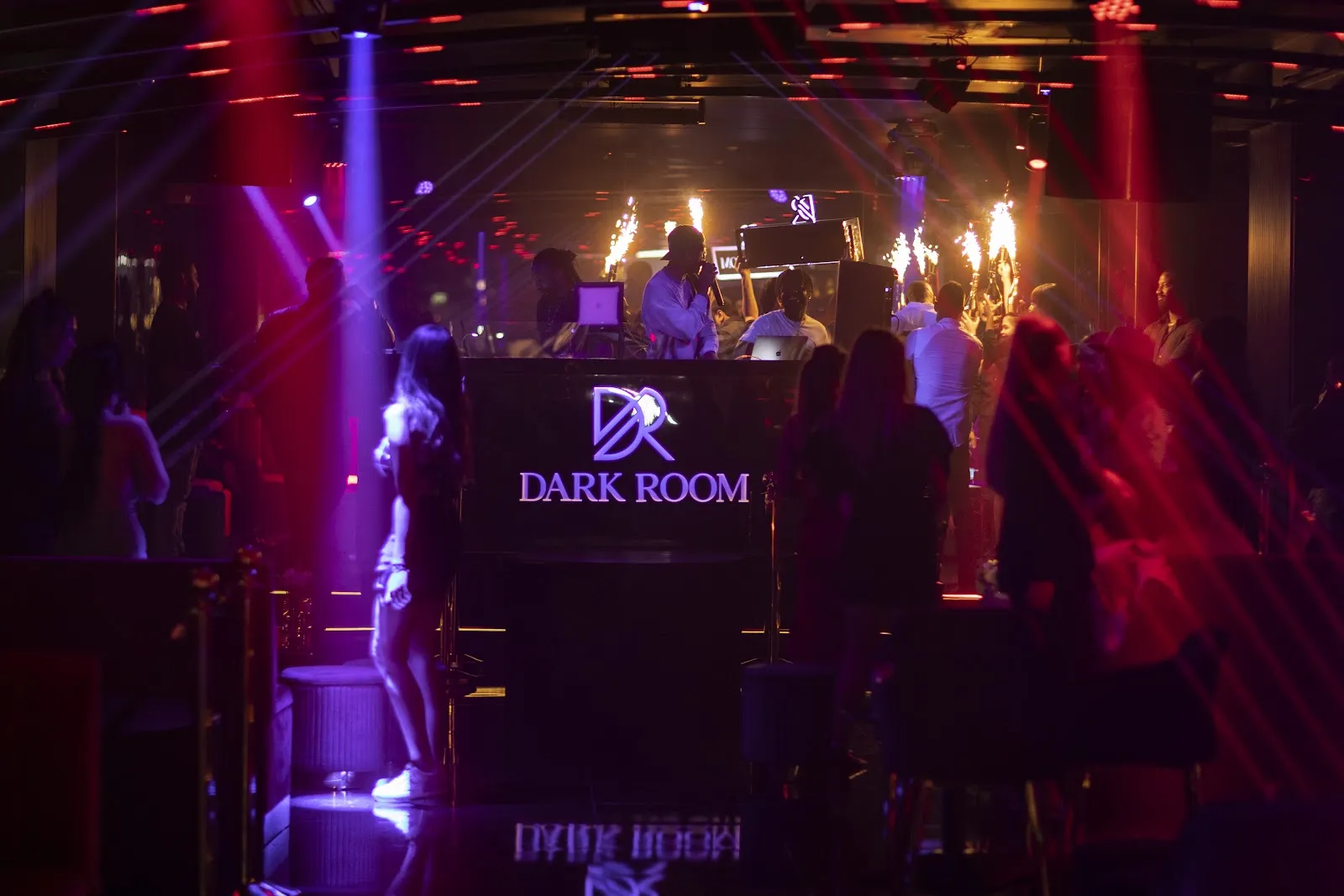 DJ booth with purple lighting and a glowing logo in the main room