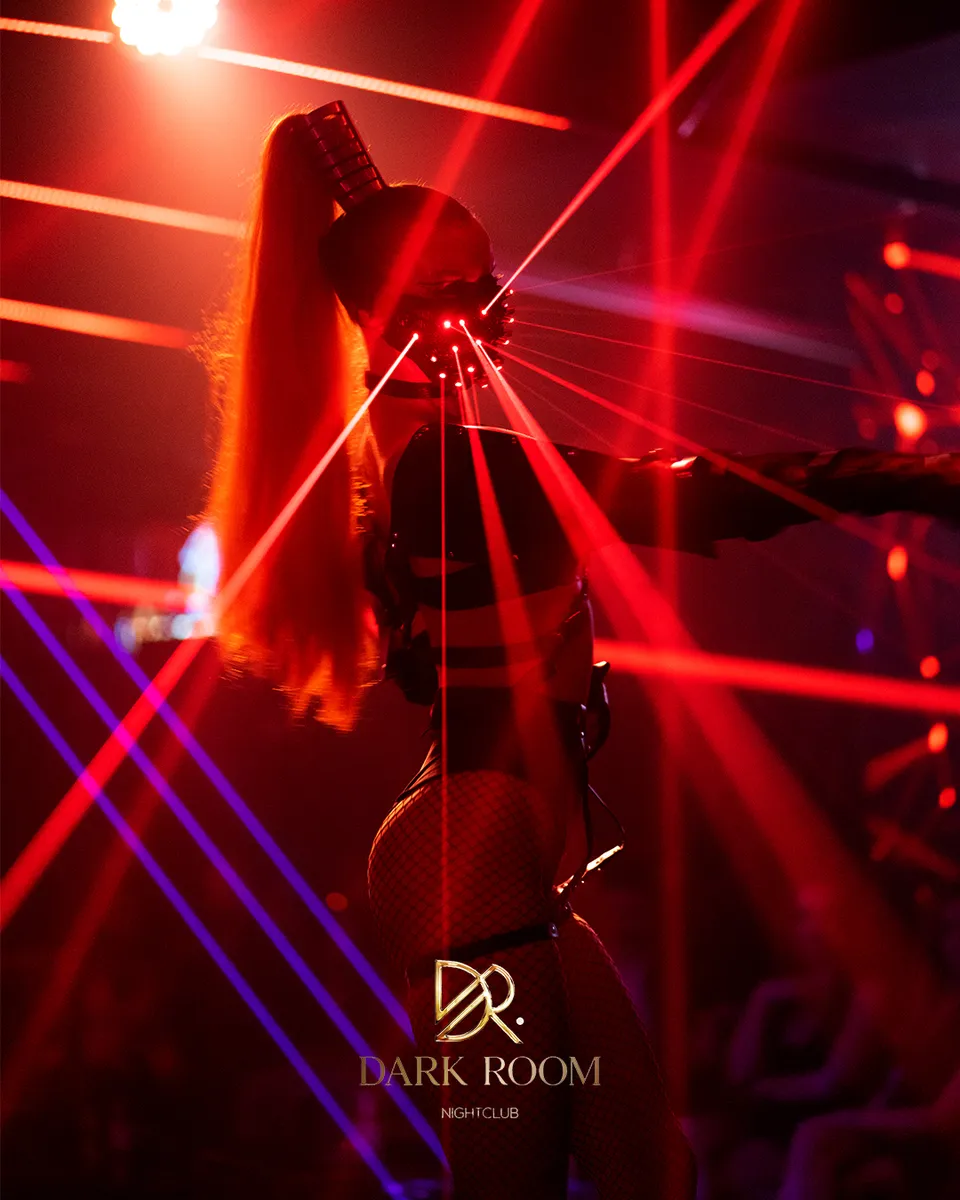 Performer with laser gloves under red lights on the dance floor at Dark Room Dubai Night Club